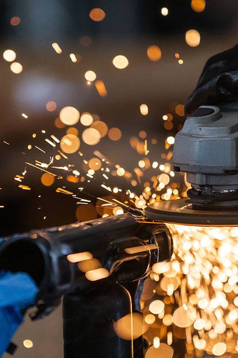 cropped image orbital metal grinder used for millwright services being pressed against a metal piece creating a shower of sparks